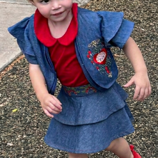 Girl wearing the HeartBrain three-piece denim set with tiered skirt, red collared top, and embroidered bolero jacket, Only For Princesses.