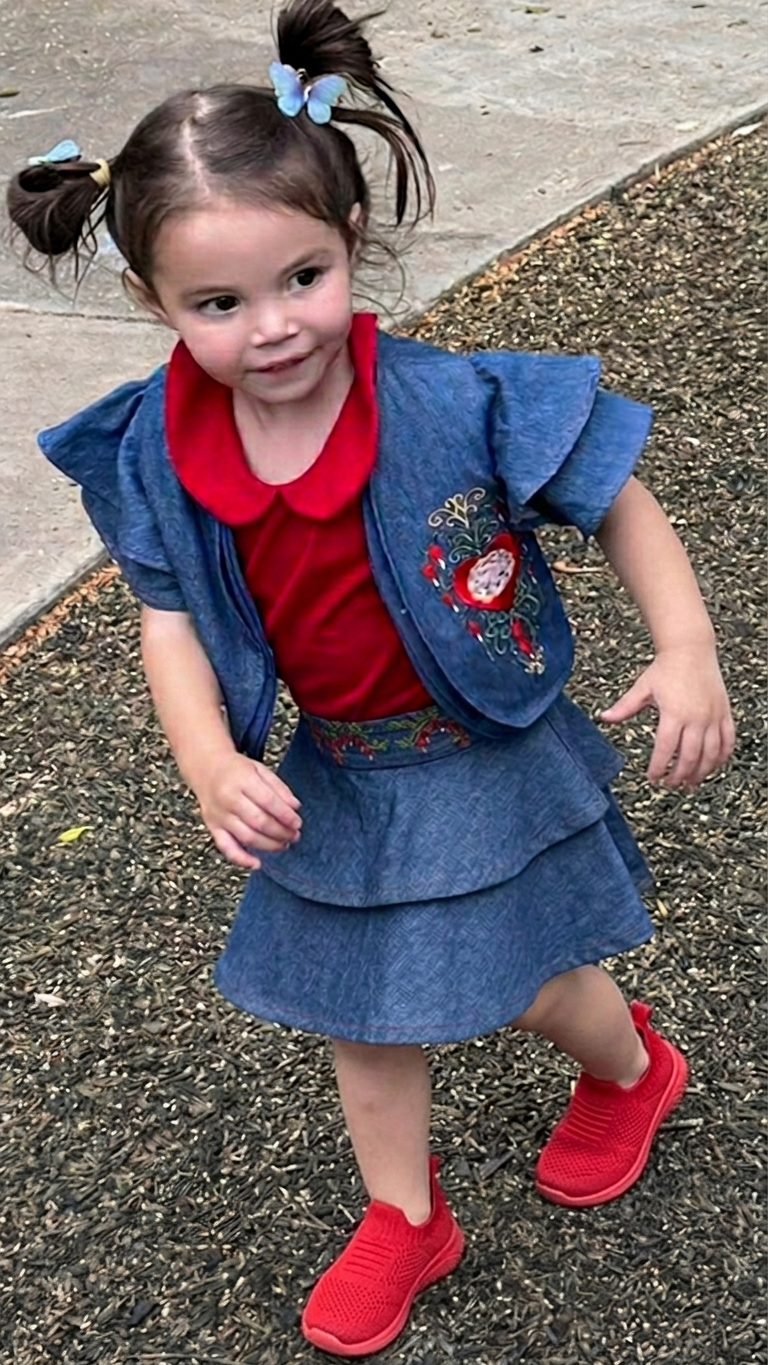 HEARTBRAIN COLLECTION, LOLA IN SKIRT Girl wearing the HeartBrain three-piece denim set with tiered skirt, red collared top, and embroidered bolero jacket, Only For Princesses.